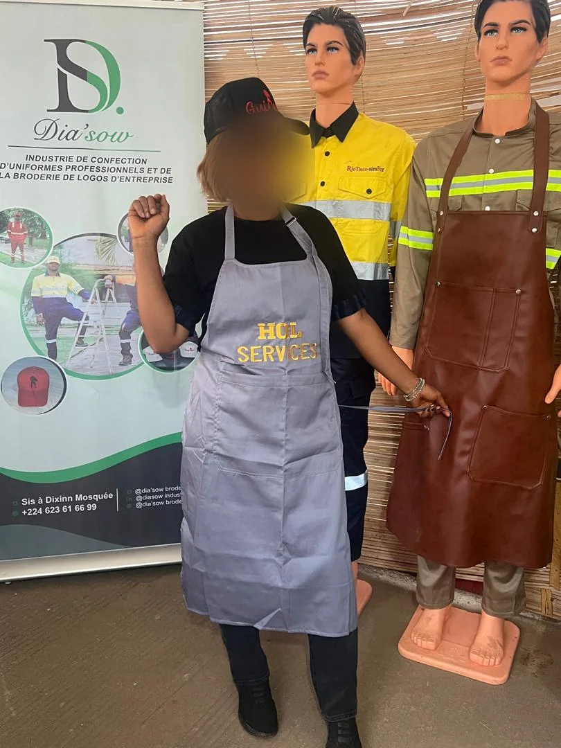 Tablier gris de service porté, visage flouté, réalisation DIASOW en Guinée